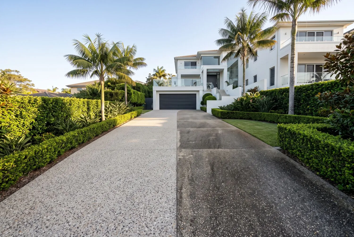 Driveway half cleaned, showing the difference against stained concrete